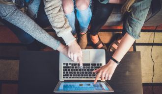 trois personnes pointant du doigt un écran d'ordinateur portable