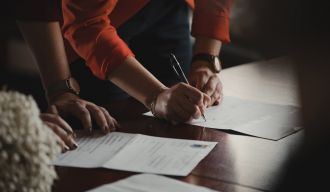 deux personnes consultant des documents, dont une qui signe