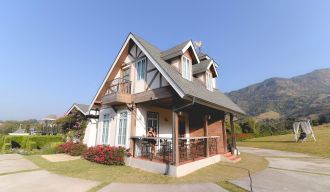 une maison blanche, grise et marron sous un ciel bleu