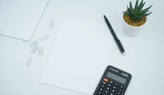 une calculatrice, un stylo, des feuilles et une plante sur une table
