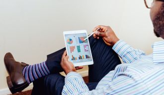 un homme assis qui consulte des graphiques sur sa tablette