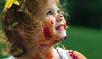 une petite fille qui a joué avec de la peinture et en a partout