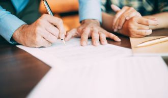 une personne masculine signe un document avec un stylo