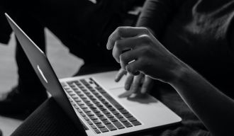 photo en noir et blanc de quelqu'un tapant au clavier de son MacBook